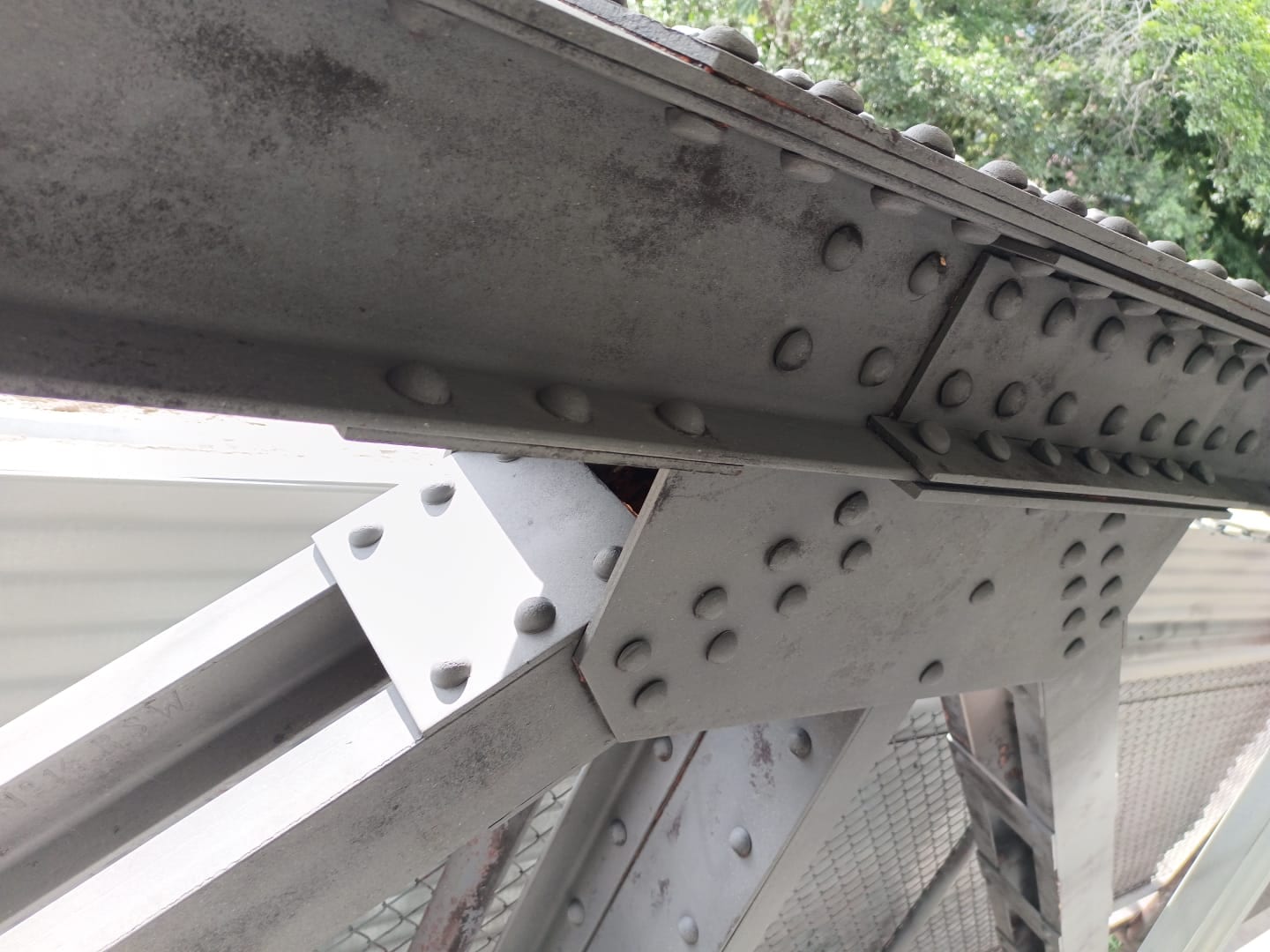 Unión empernada de una estructura de acero gris, vista desde abajo.